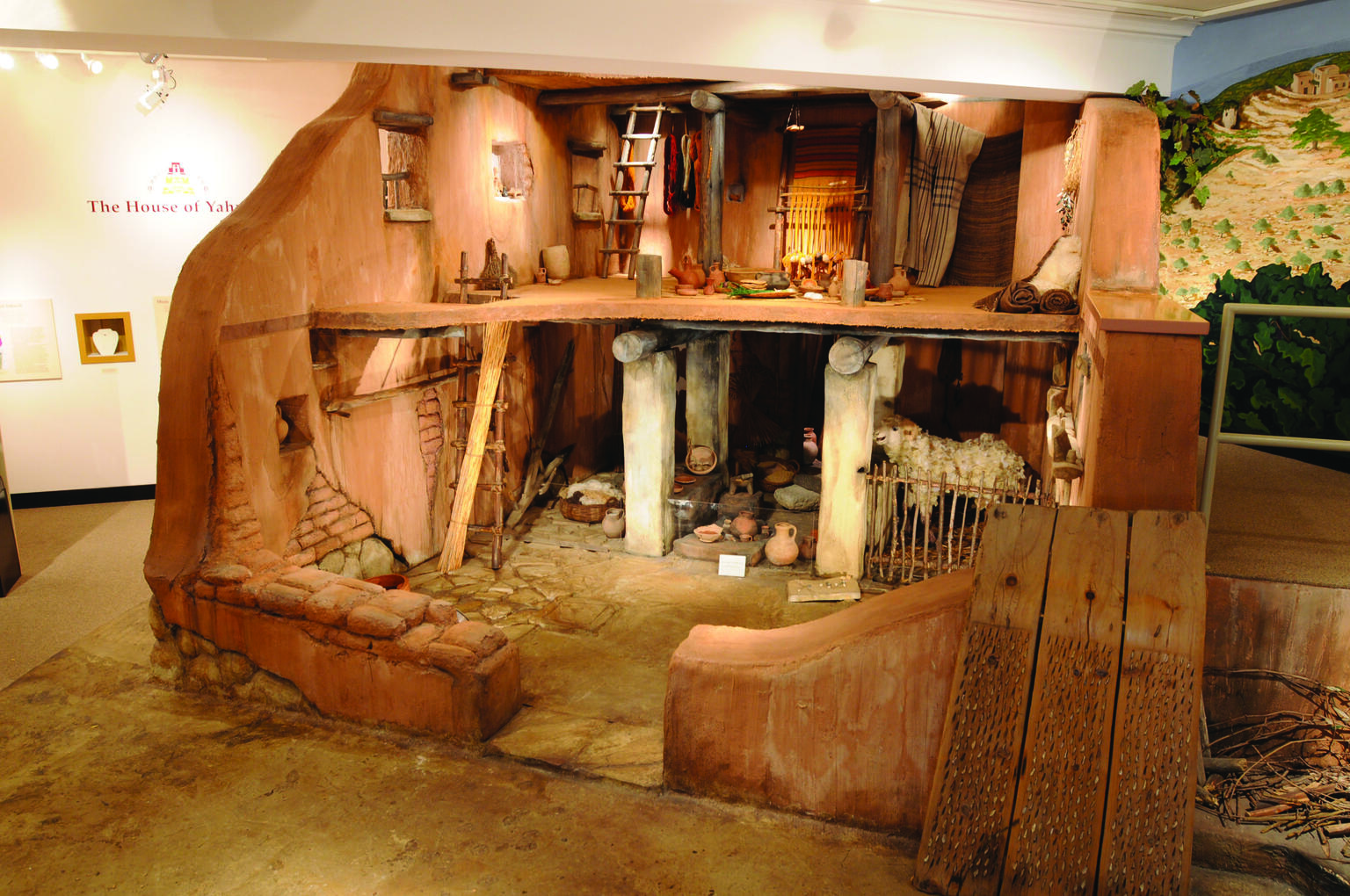 Model of two-story house, with upper floor consisting of living space and bottom floor with space for animal stalls and cookware.