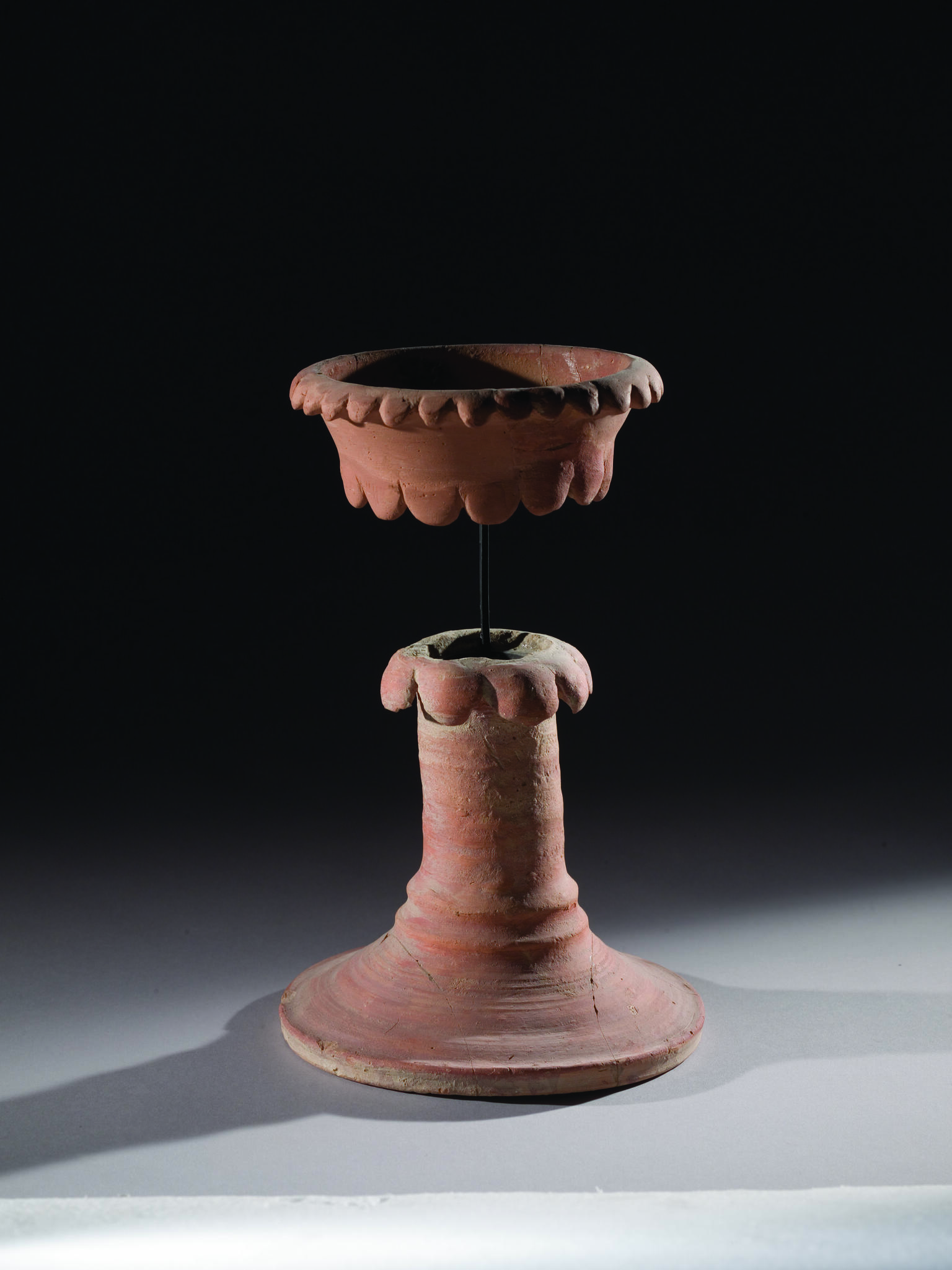 Ceramic chalice with tall, hollow stand and bowl in a separate piece on top and secured to bottom of chalice with a rod.