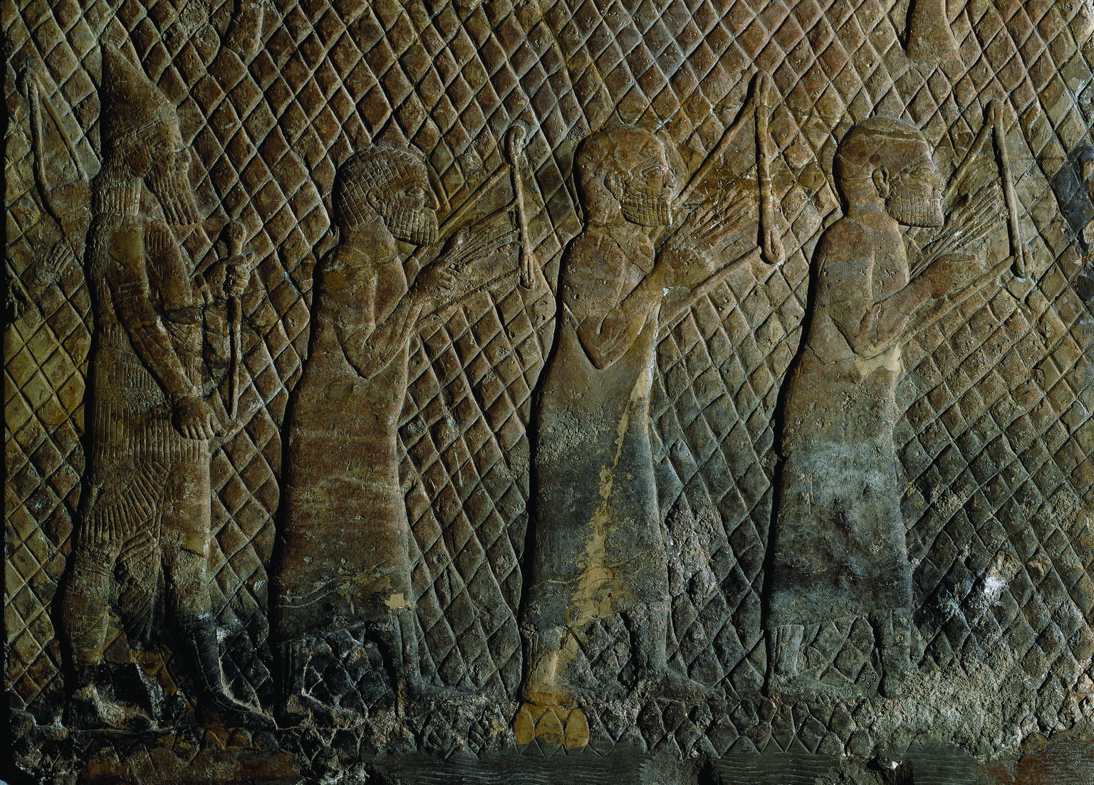 Wall relief showing three bare-headed musicians in tunics holding stringed instruments against their chests, with bearded soldier holding weapon behind them.