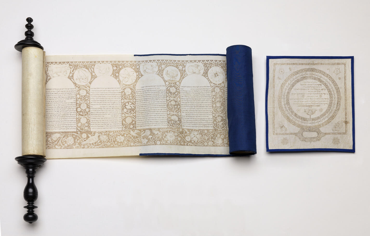 Partially unraveled scroll with Hebrew text in rounded columns and decorative border and individual page next to it with Hebrew text and circular border. Partially unraveled scroll with Hebrew text in rounded columns and decorative border and individual page next to it with Hebrew text and circular border.