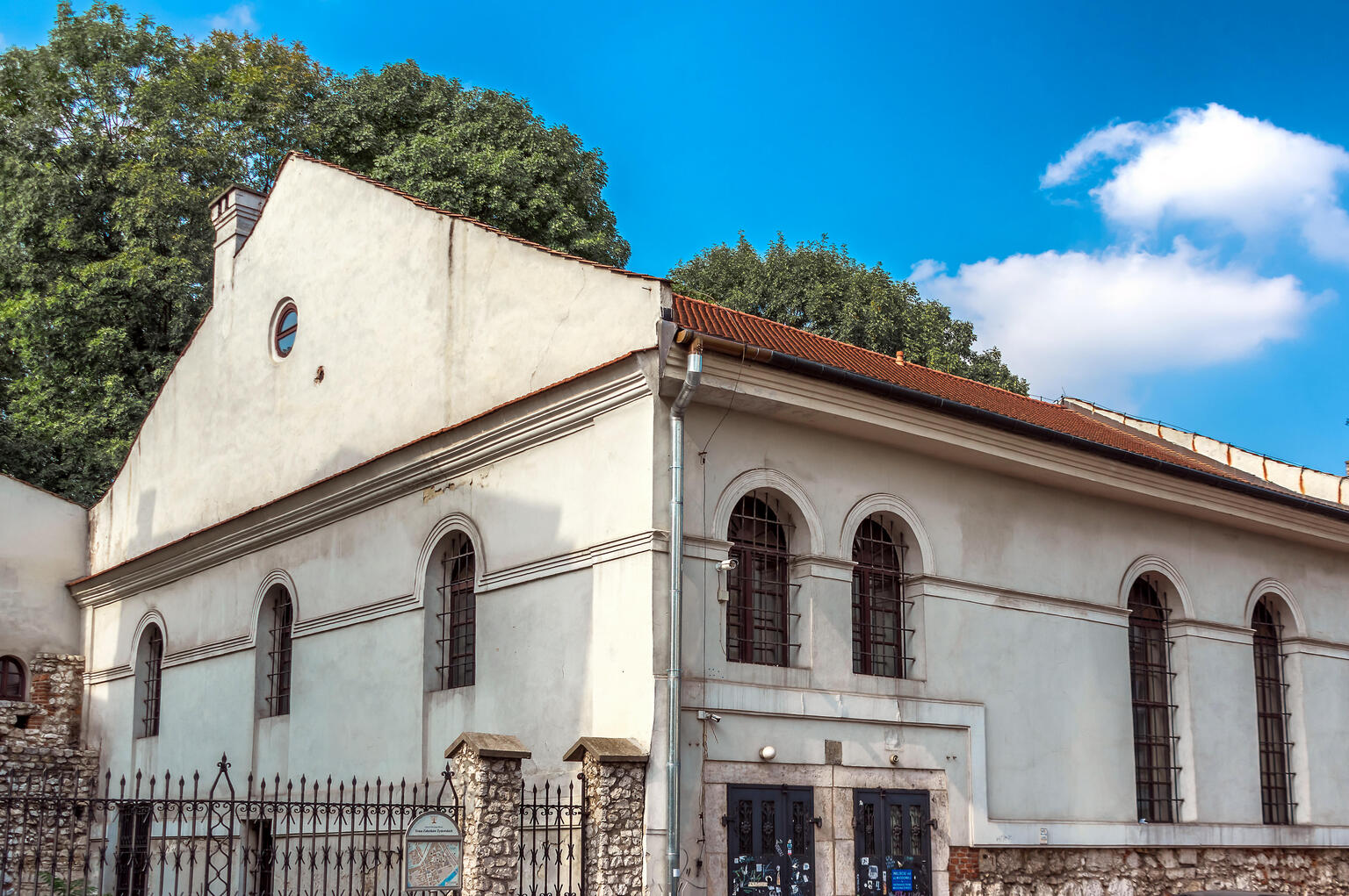 Photograph of building exterior with curved windows and gated courtyard to left.