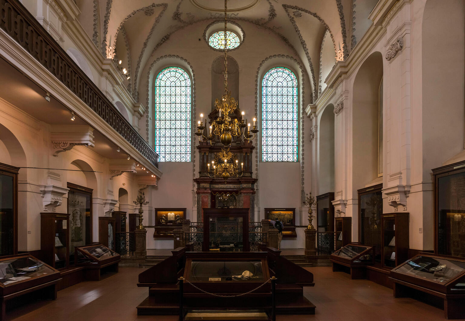 Photograph of room interior with Torah ark, chandelier, and tall arched doorways.