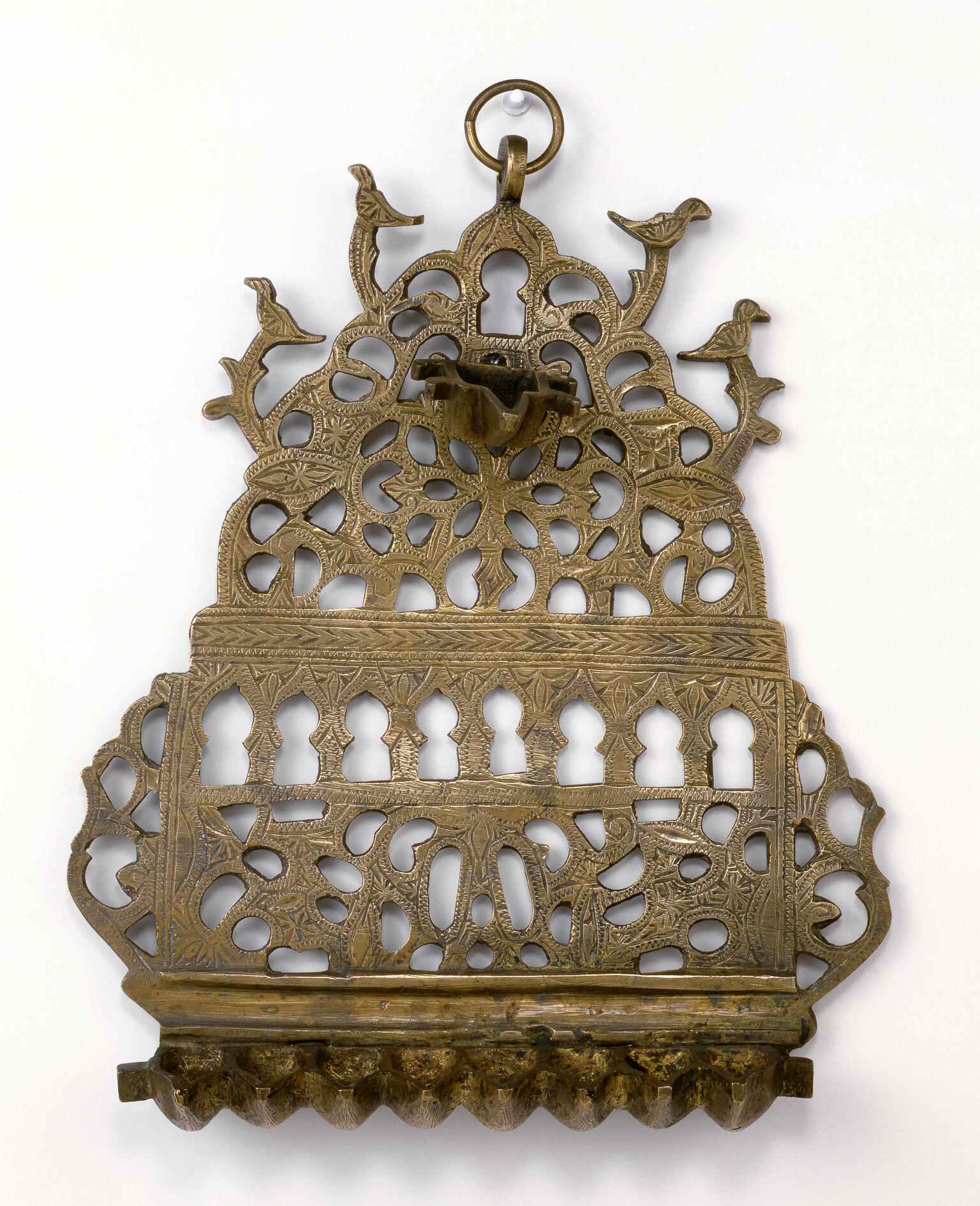 Oil lamp with cut-outs in various shapes, with row of eight cups on bottom and one cup on top.