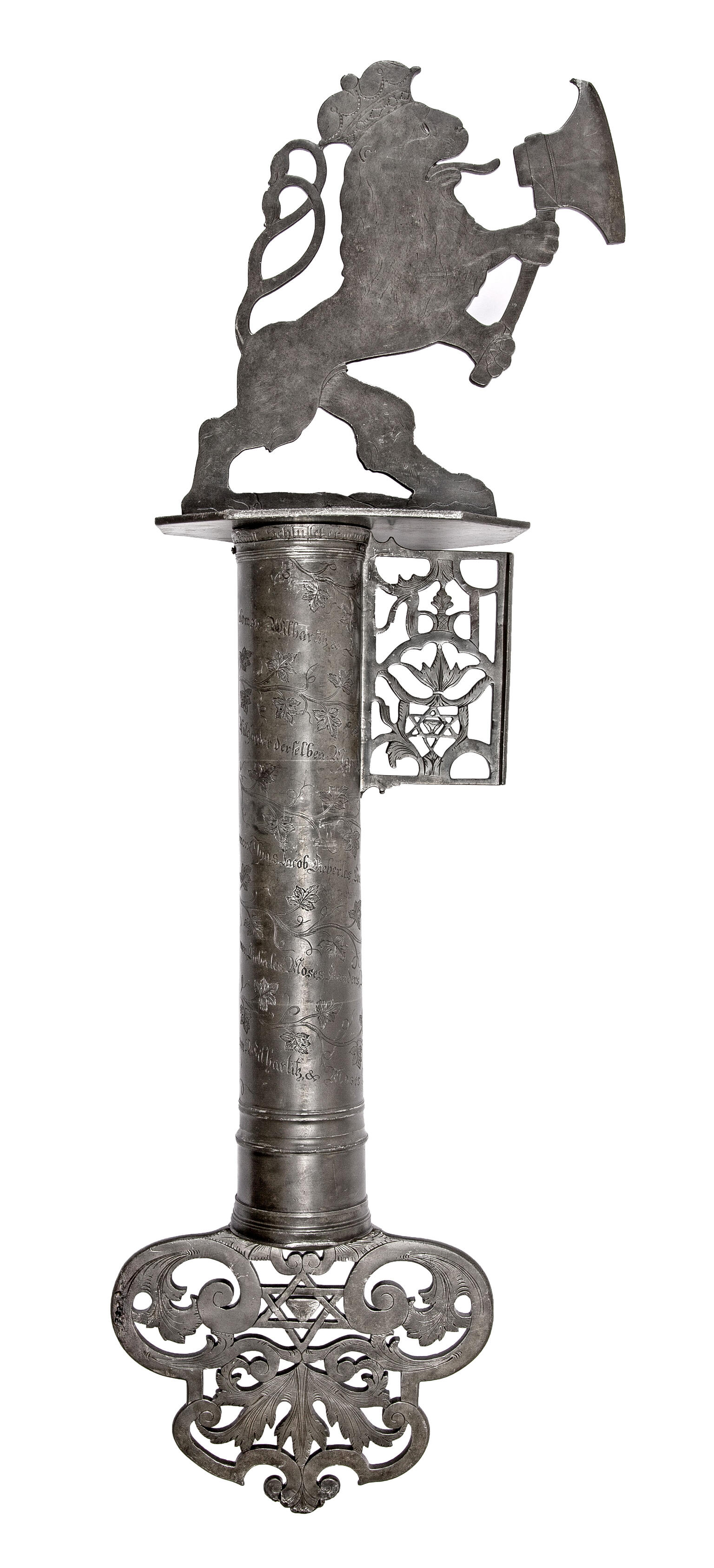 Metal cylindrical object with carving of lion holding axe on top, and decorative carving on bottom. 