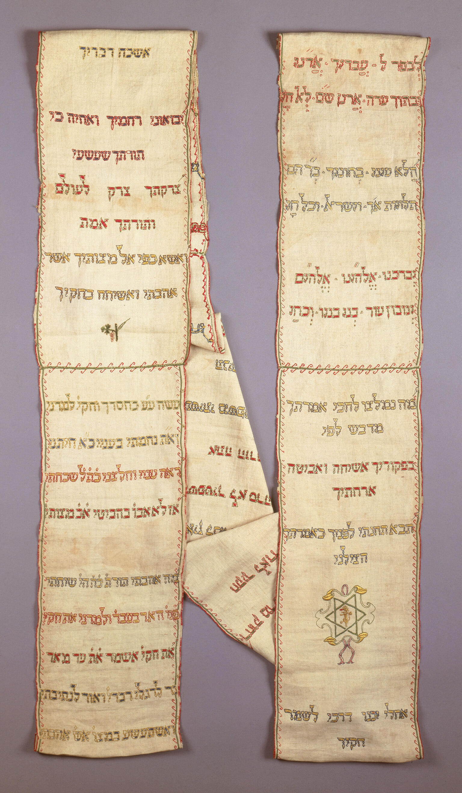 Rectangular cloth arranged in two columns embroidered with Hebrew text and small Star of David on right side. 