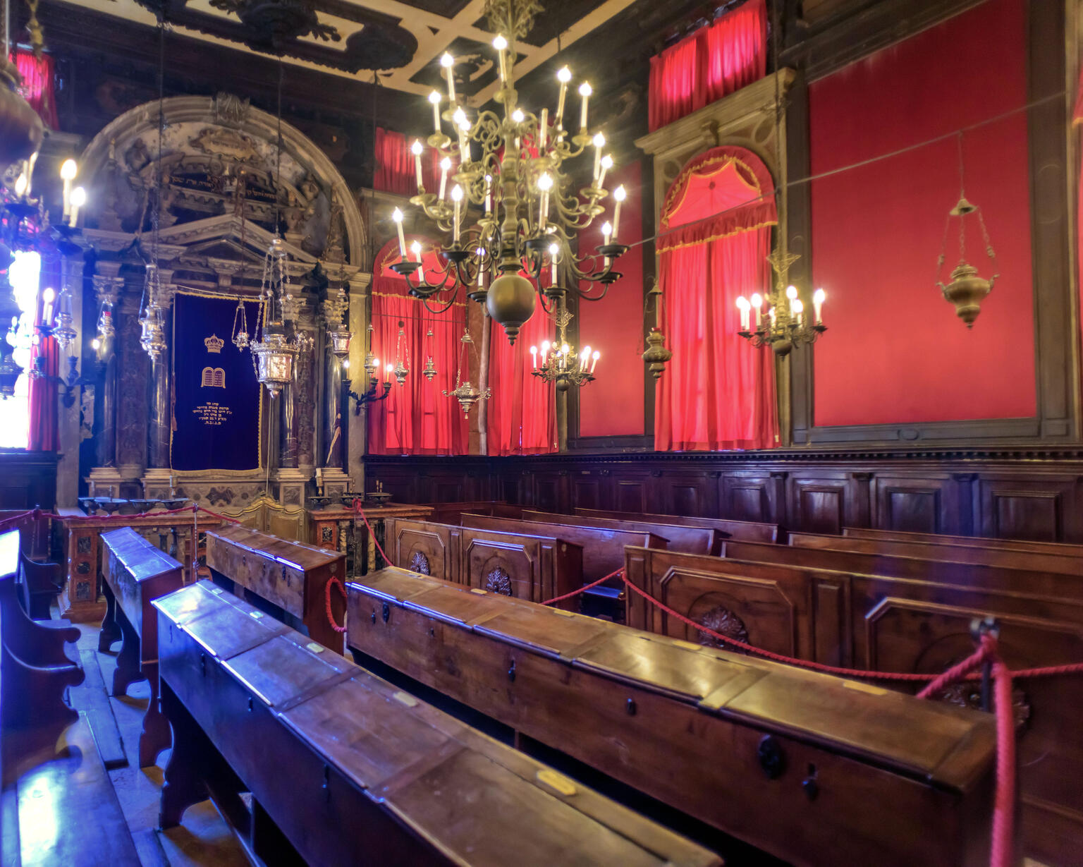 Photograph of room with rows of pews, curtains on right-hand wall, and columned archway on back wall. 