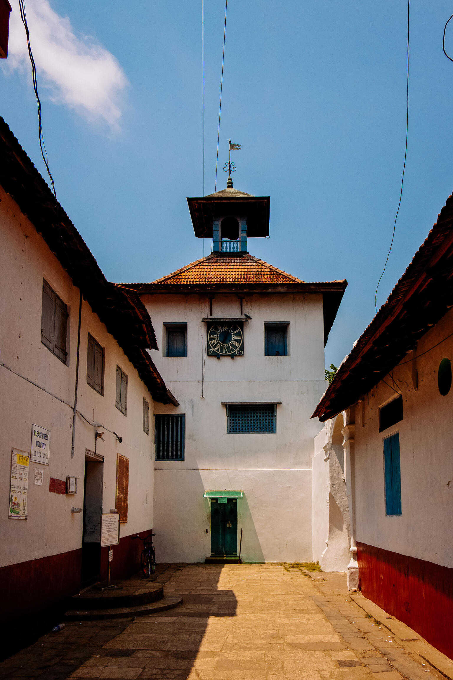 Exterior photograph of intersecting walls of stone buildings with tile roofs.