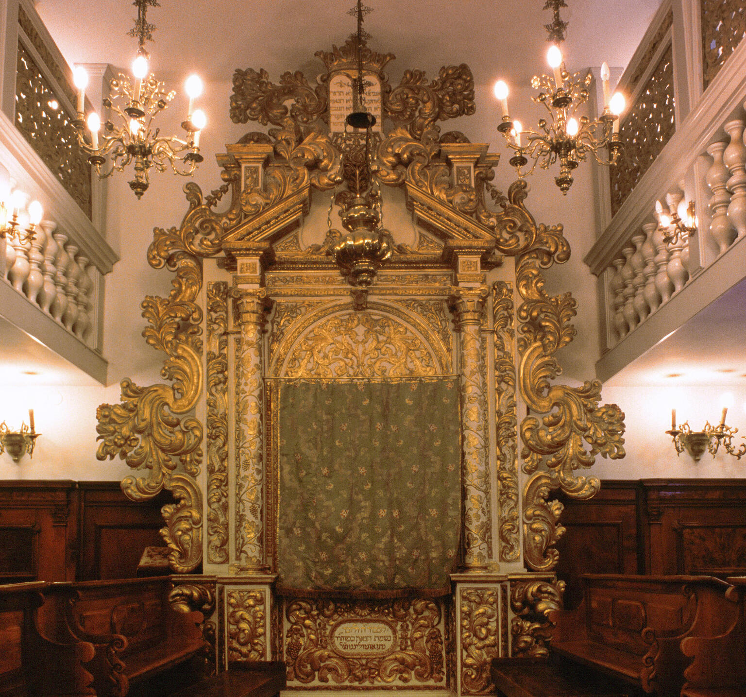 Photograph of room with large carved Torah ark with pews on either side of room and screened second-floor balcony. Photograph of room with large carved Torah ark with pews on either side of room and screened second-floor balcony.
