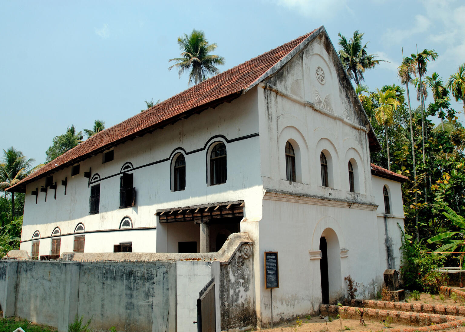 Exterior photograph of stone building with tile roof and arched windows.