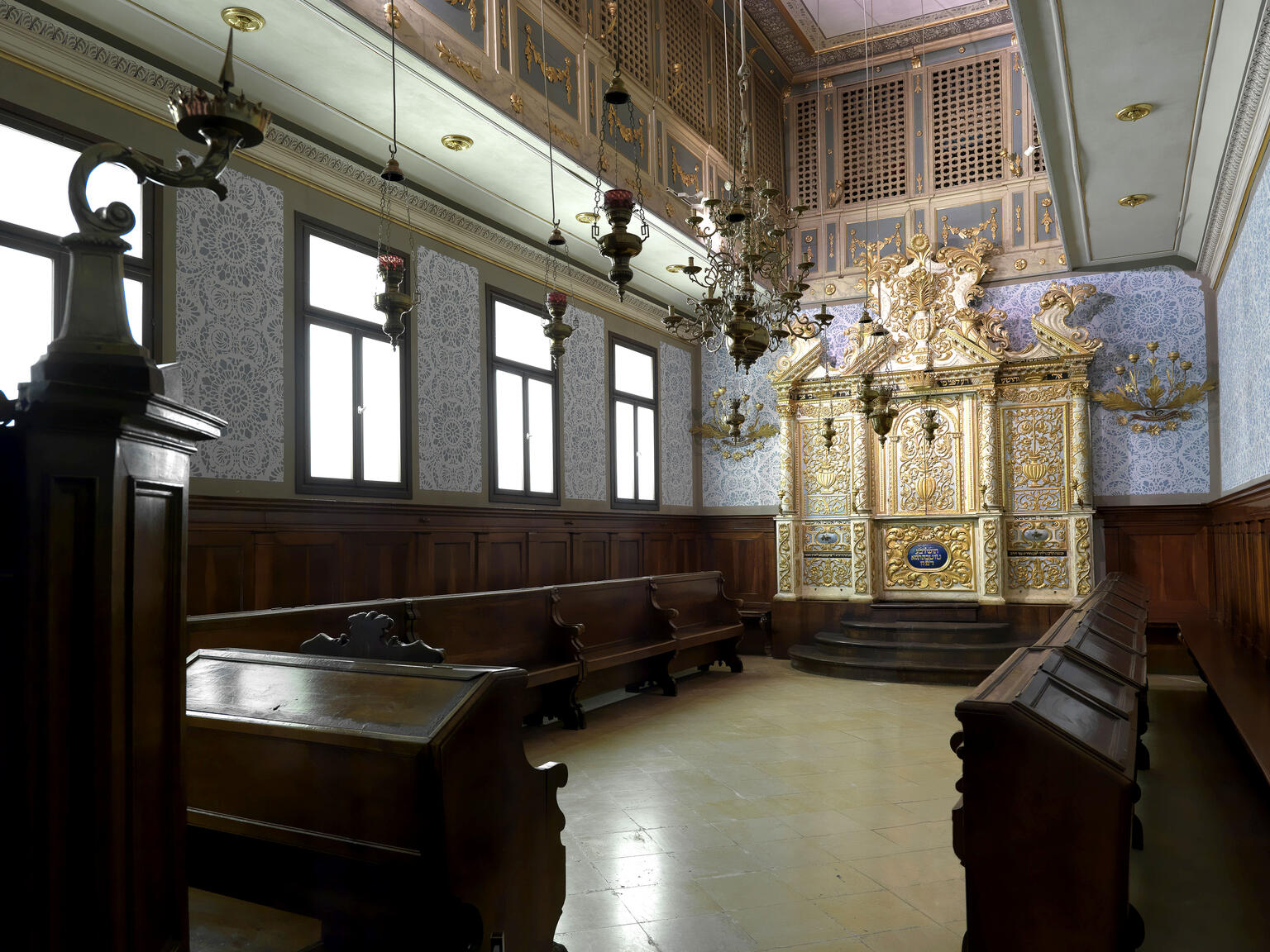 Photograph of room with pews along walls and gold Torah ark in center of back wall.