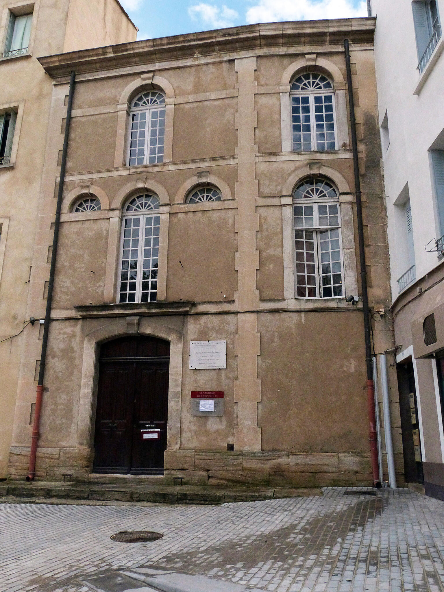 Exterior photograph of building facade with arched windows. 