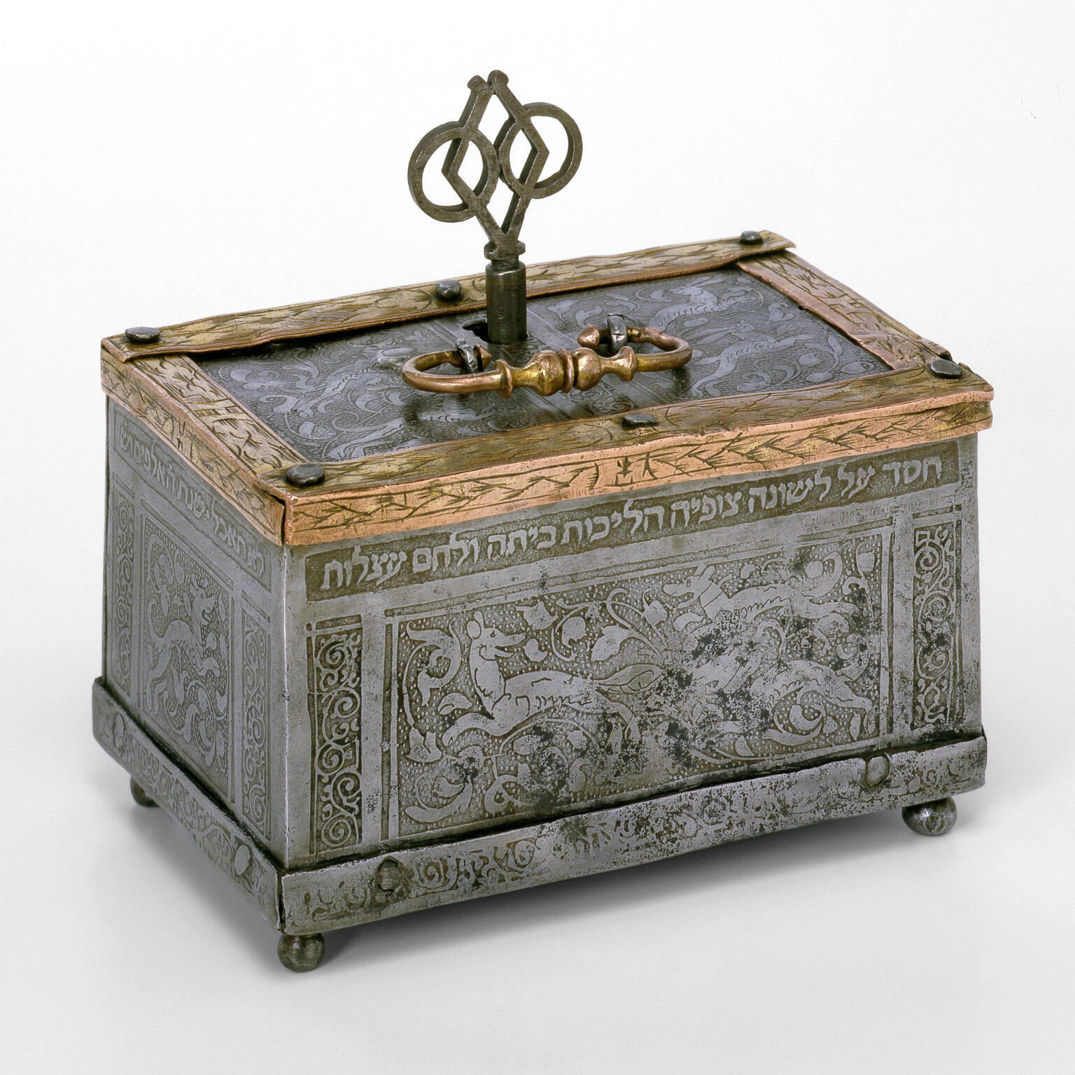 Metal box engraved with images of dogs and foliage, with handle and key on top. Metal box engraved with images of dogs and foliage, with handle and key on top.
