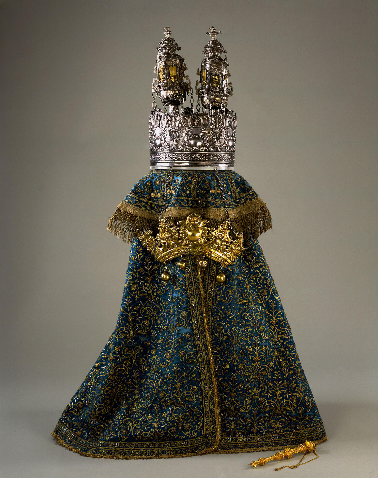 Cloth cover with embroidery and metal crown, and crown resting on top of cloth. Cloth cover with embroidery and metal crown, and crown resting on top of cloth.