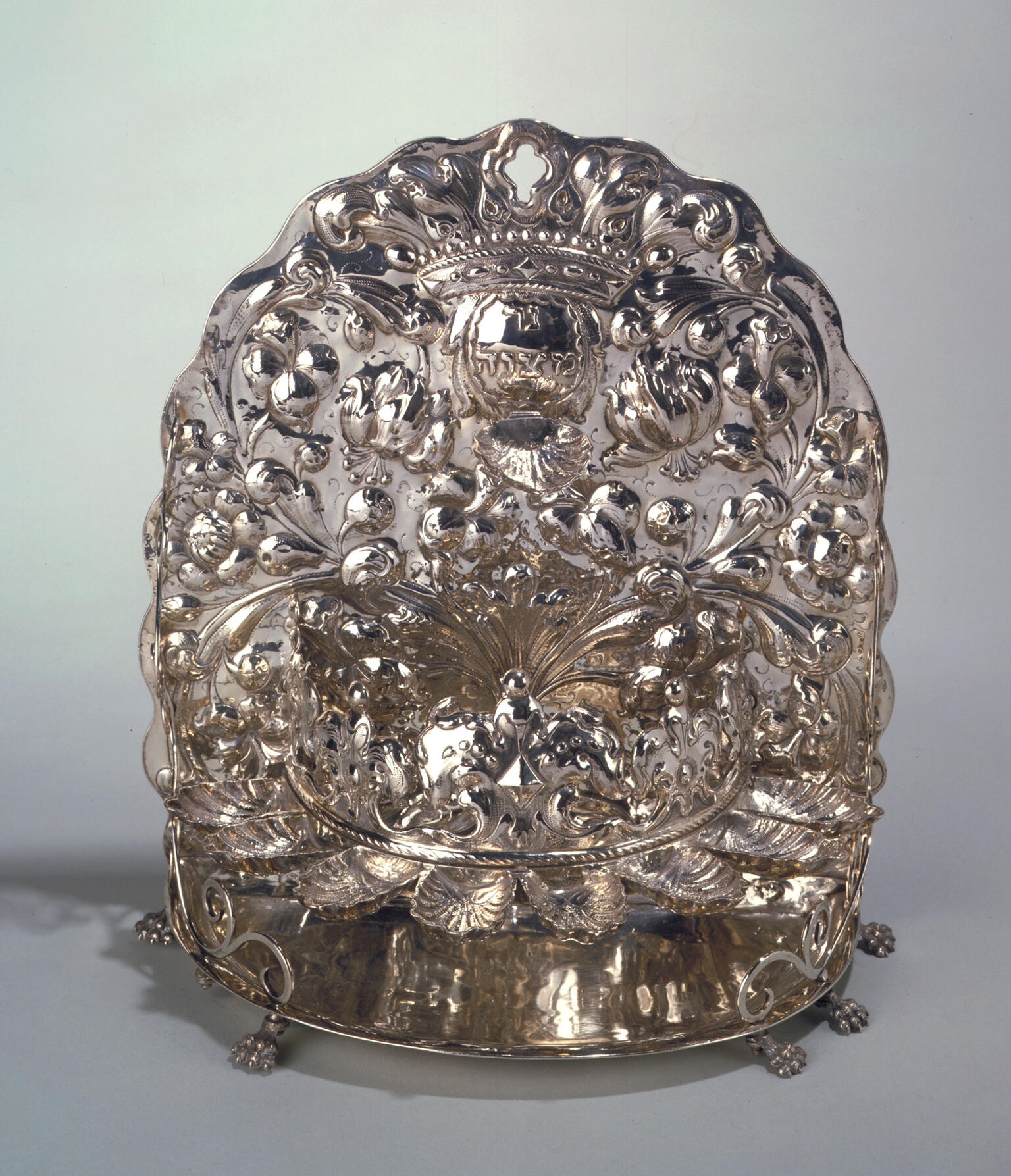 Oil lamp stamped with crown and foliage with eight cups on bottom. 