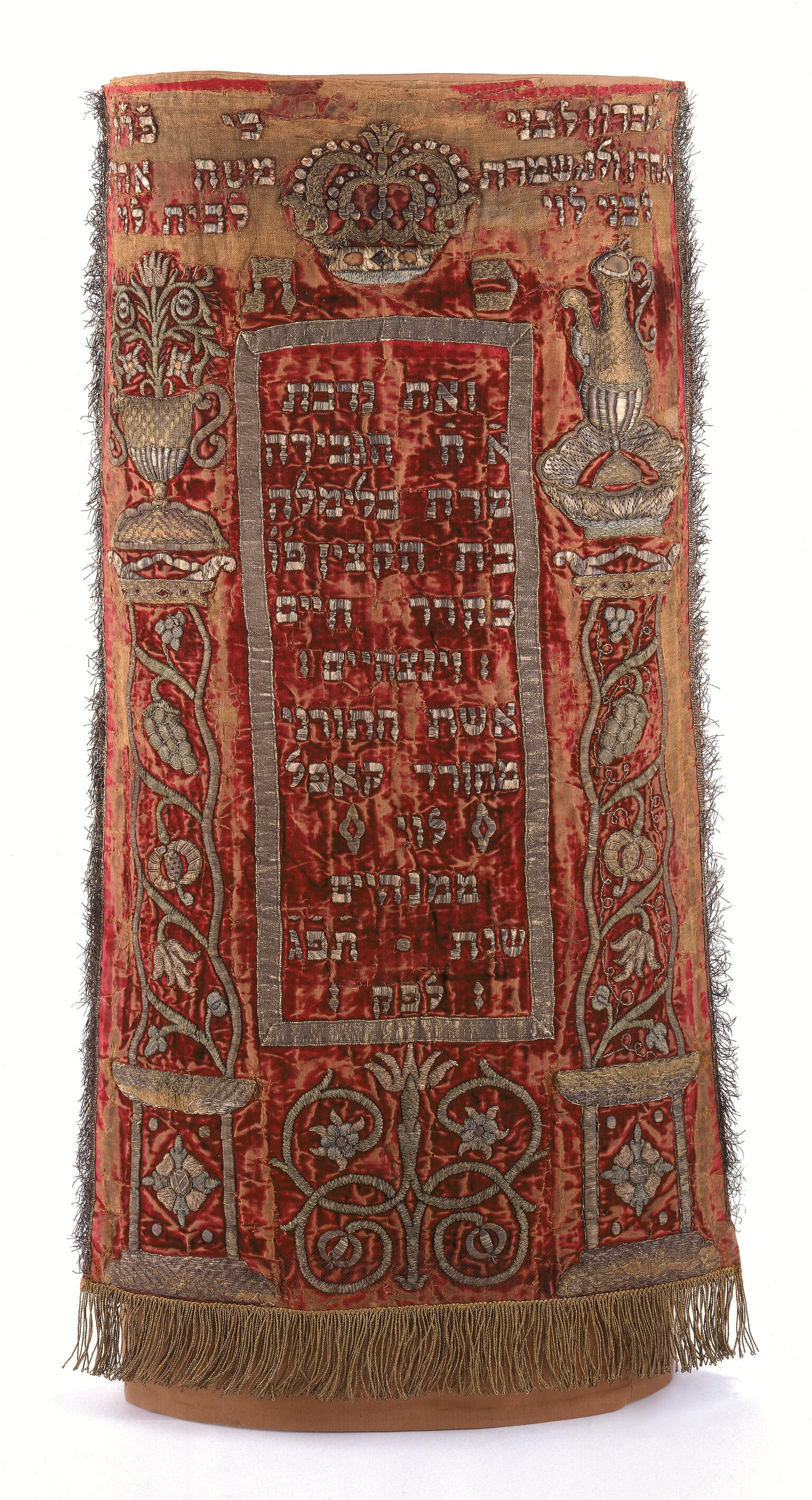 Cloth with fringe on bottom, Hebrew text on top and middle, and border of foliage. 