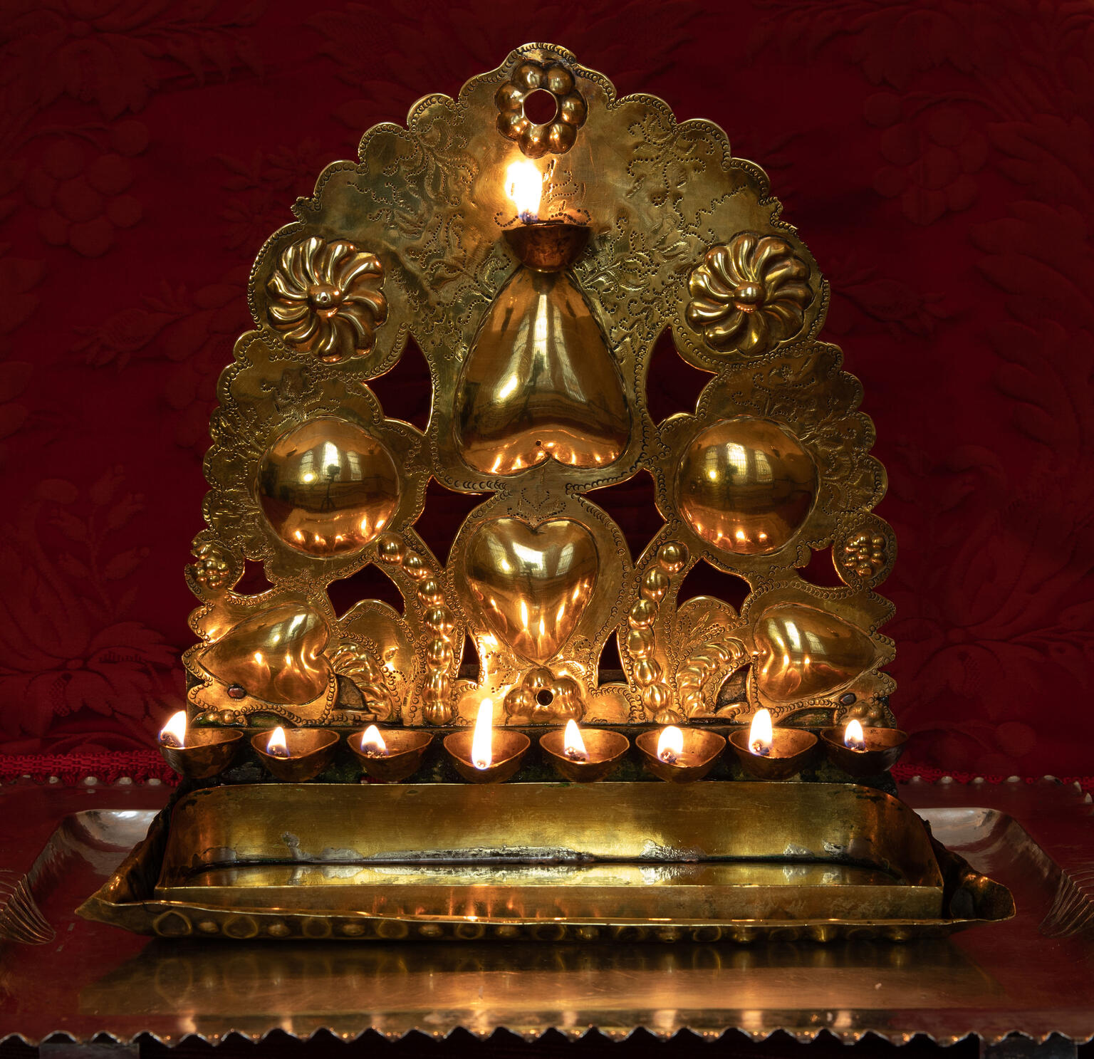 Oil lamp with row of eight cups on the bottom and scallop-shaped decorations.