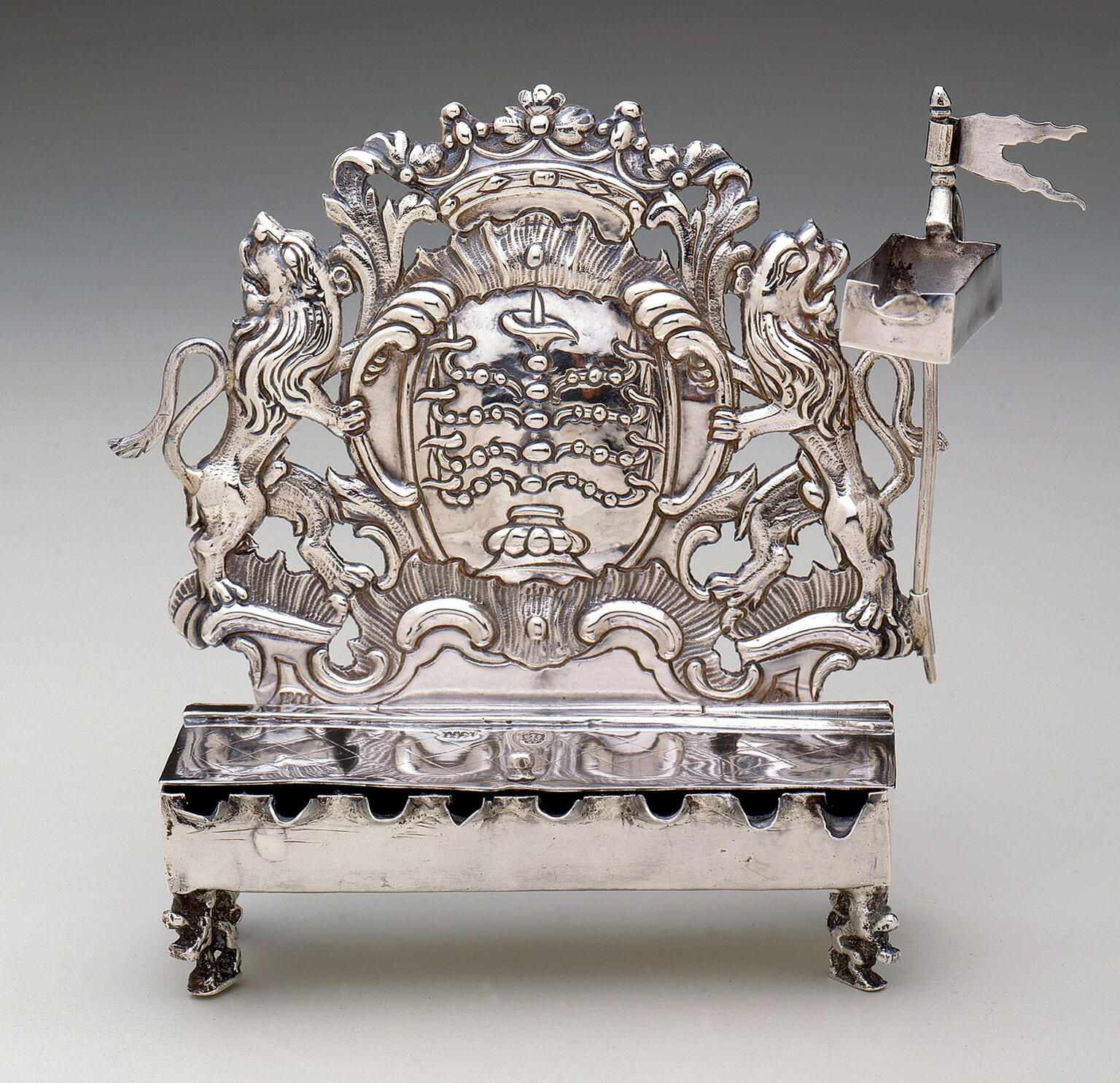 Silver oil lamp with lions on each side and crown on top. 