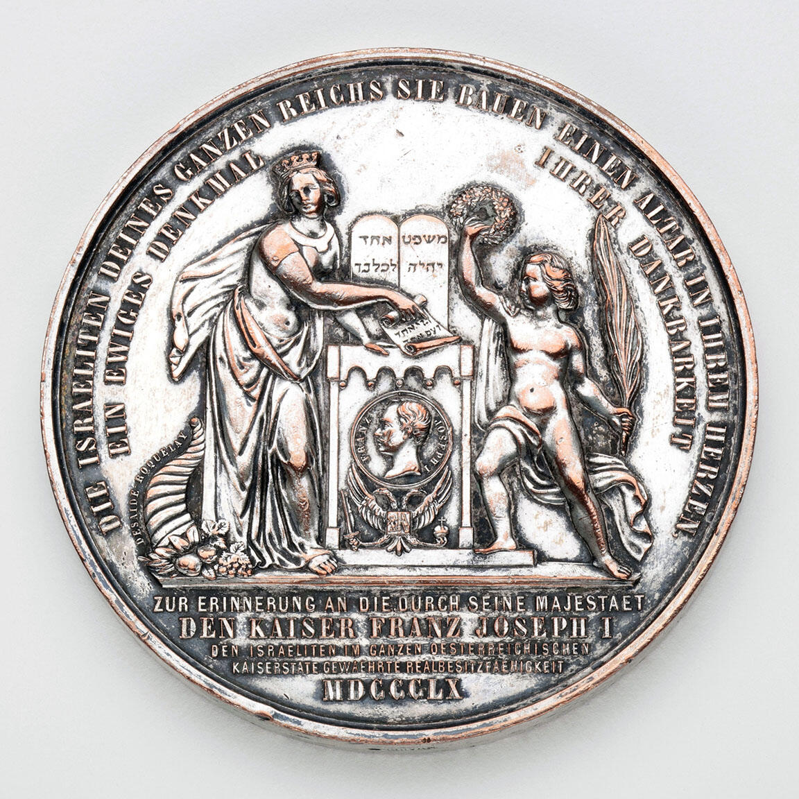 Medal depicting two figures on either side of a set of tablets and small portrait of man in center.