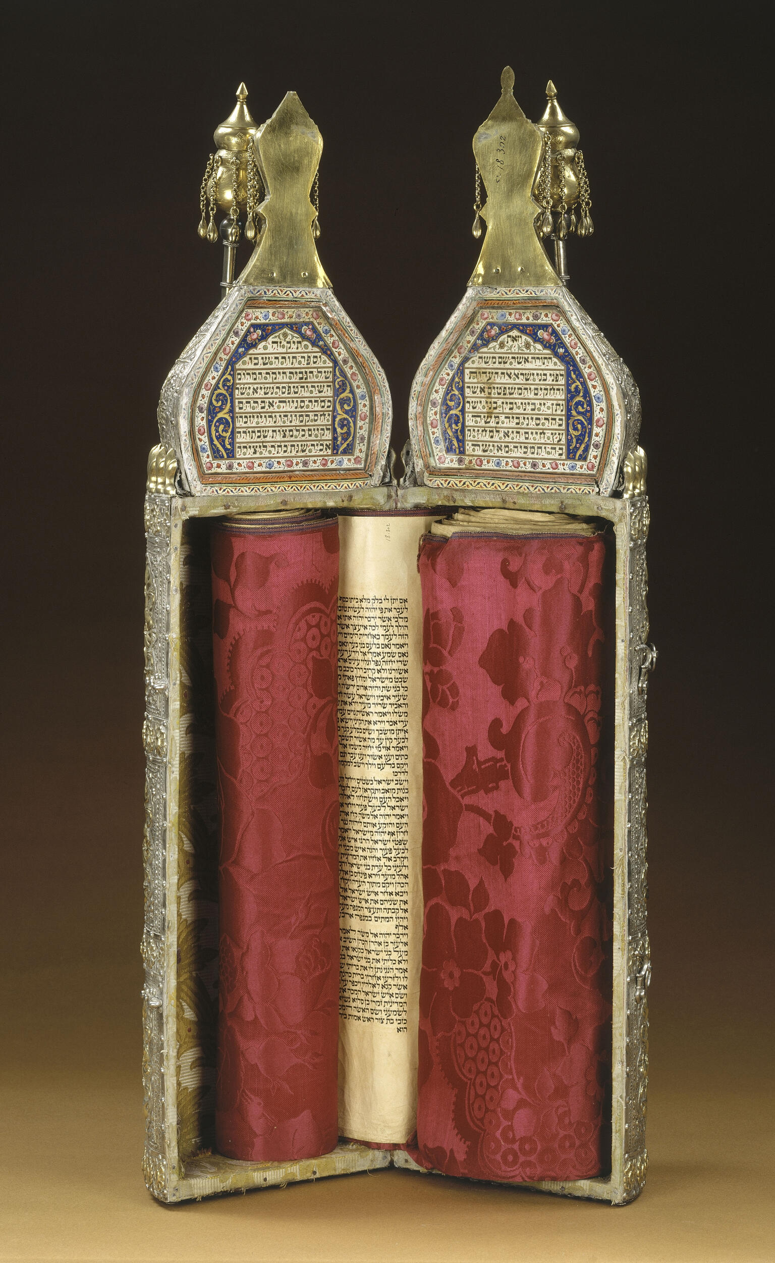 Ornately decorated cylindrical case with Hebrew writing on top and scroll inside; closed cylindrical case with ornate decoration.