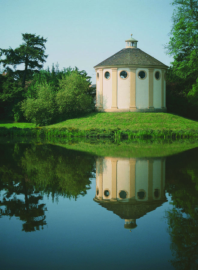 Photograph of round building in a park, reflected in pond. Photograph of round building in a park, reflected in pond.