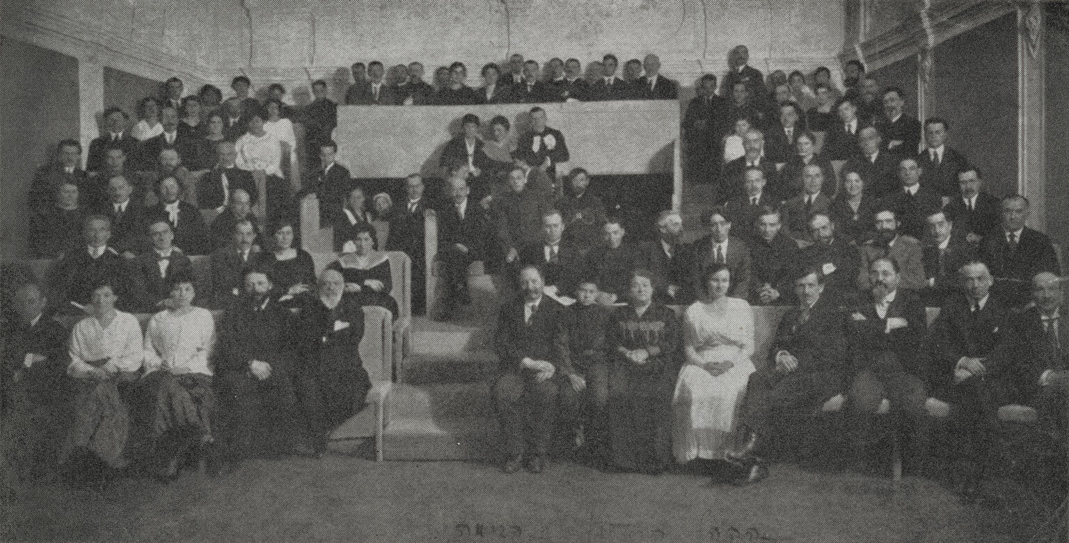 Photograph of many people sitting in rows. Photograph of many people sitting in rows.