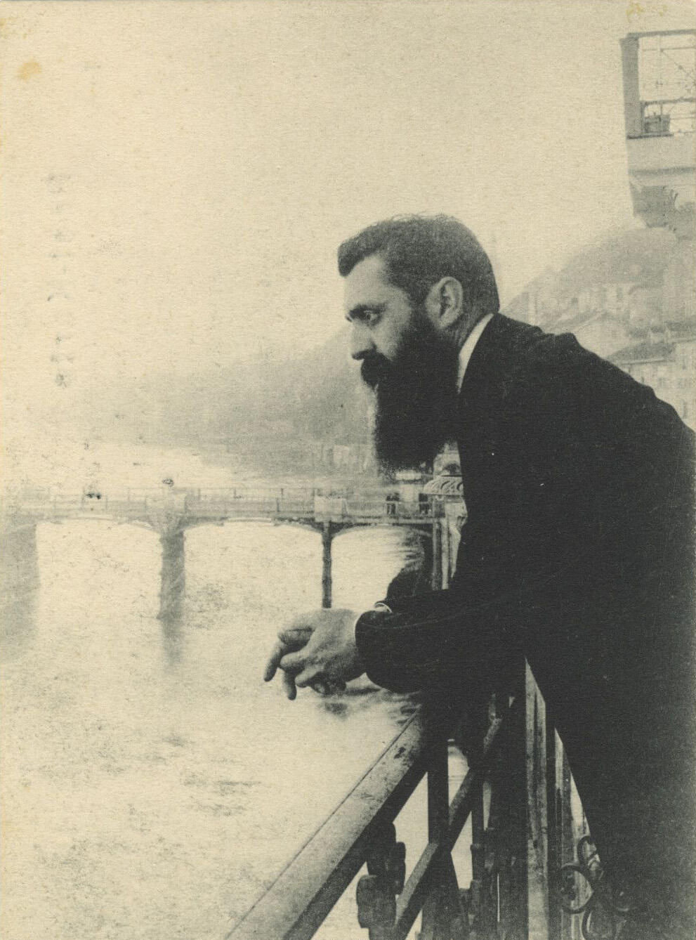 Photograph of man leaning over a bridge.