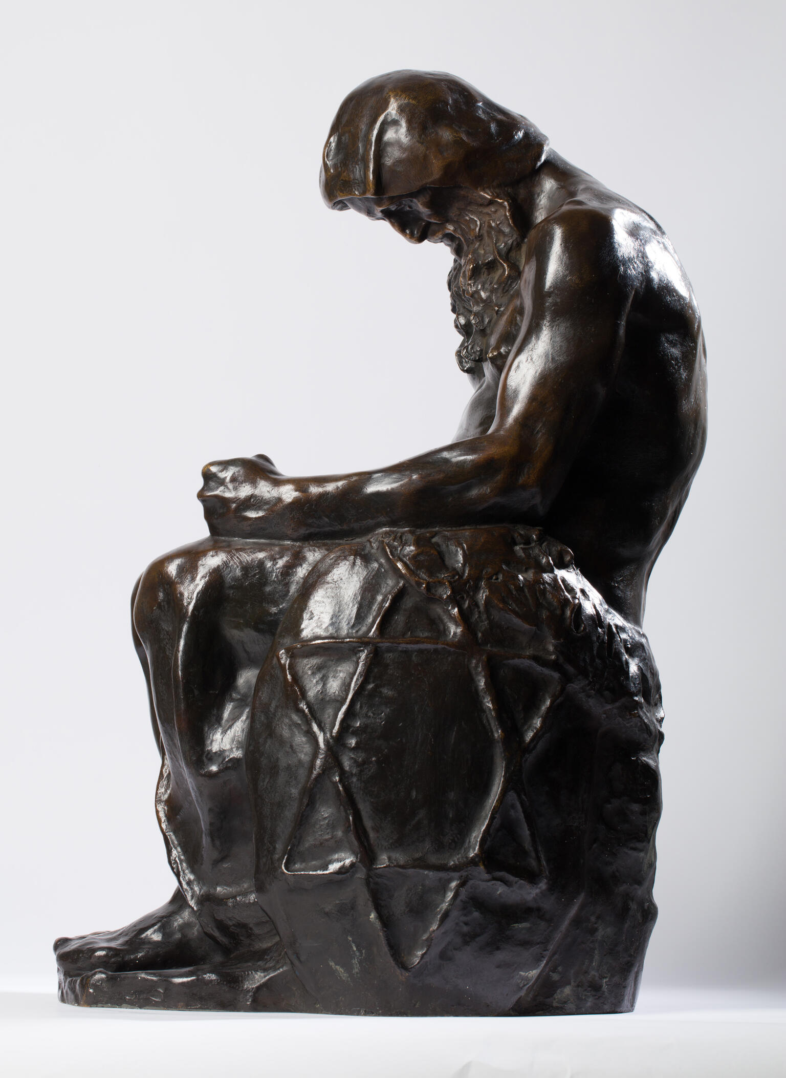 Bronze sculpture of seated figure with beard and Star of David etched onto its side.