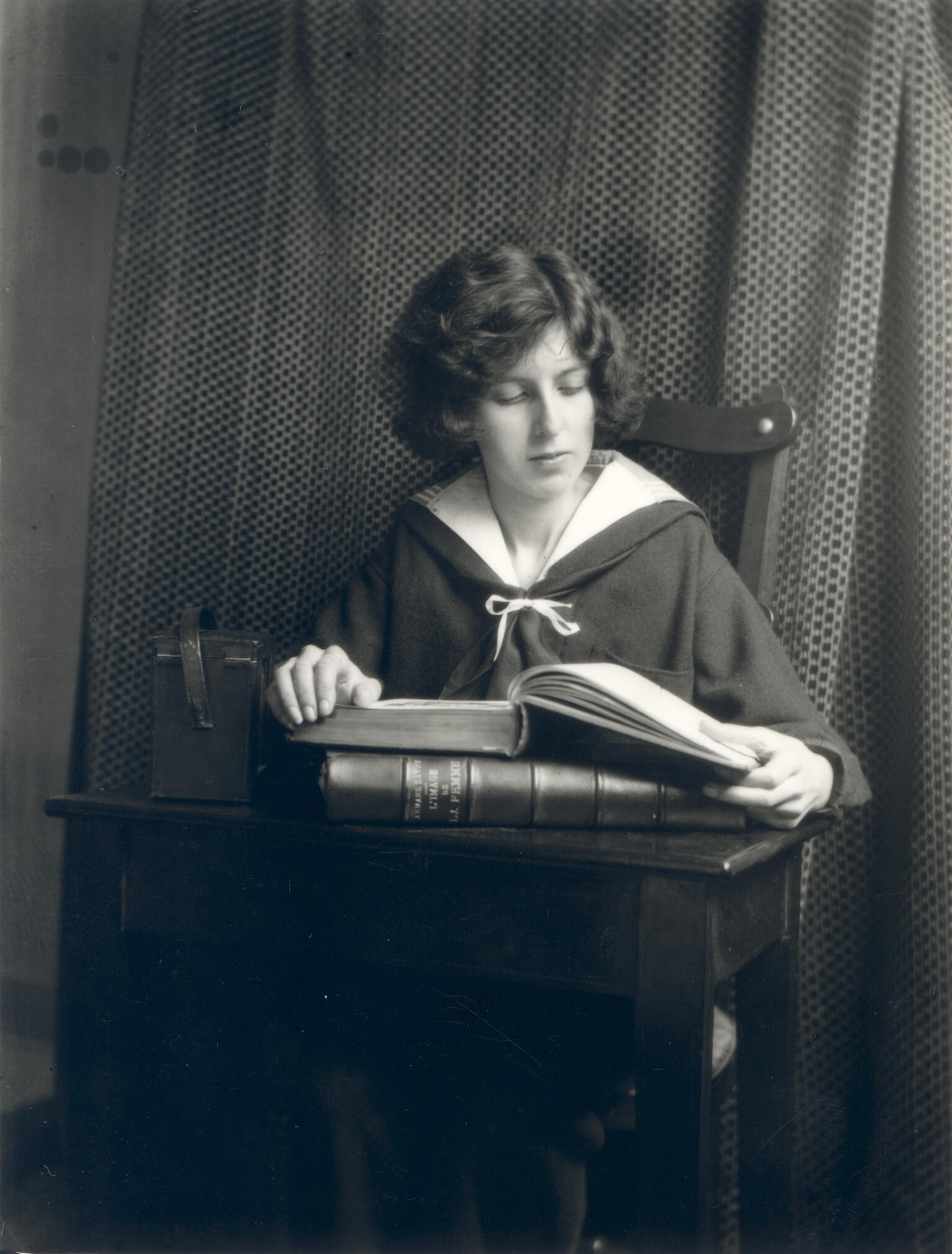 Photograph of figure seated at desk reading a book. Photograph of figure seated at desk reading a book.