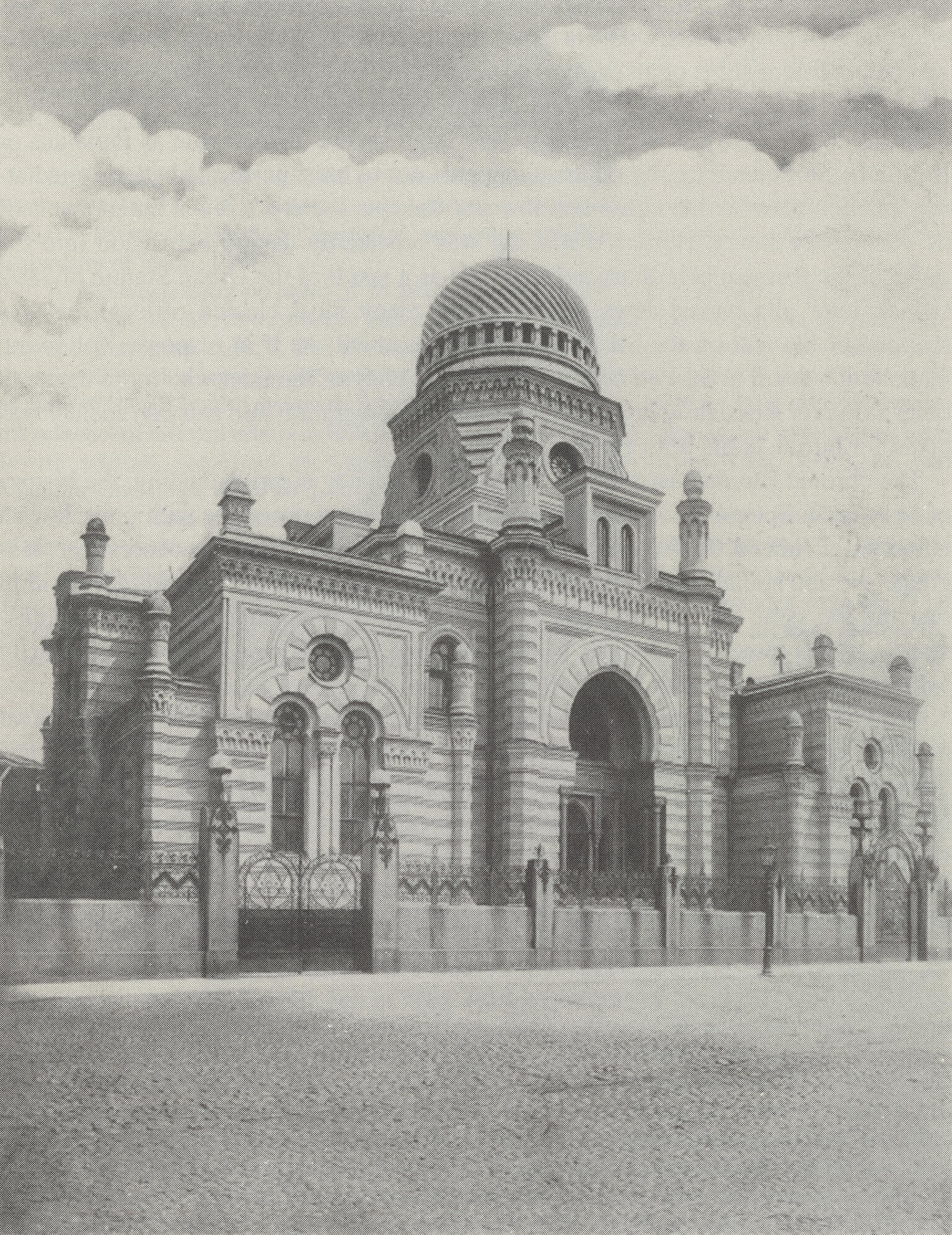 Street view of ornate building with archways, turrets, and domed roof, surrounded by fence.