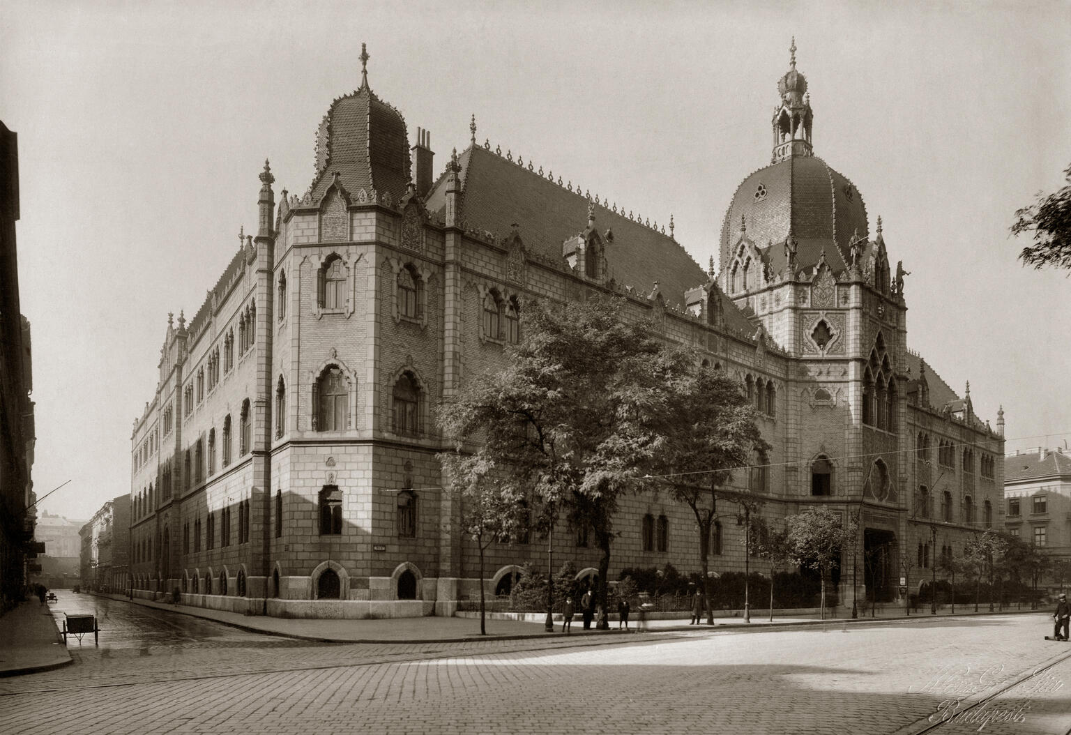 Photograph of brick building on street corner with ornate roof finials and domed roofs. Photograph of brick building on street corner with ornate roof finials and domed roofs.