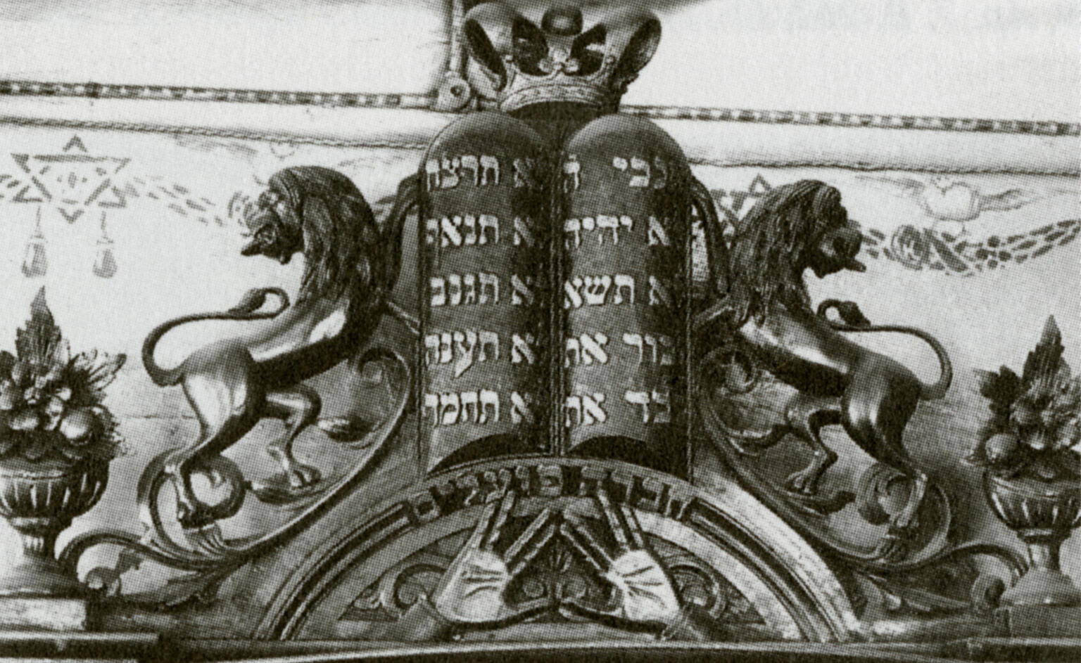 Photograph of wooden structure with two small columns of Hebrew writing with crown on top, and two sculped lions on either side. Photograph of wooden structure with two small columns of Hebrew writing with crown on top, and two sculped lions on either side.