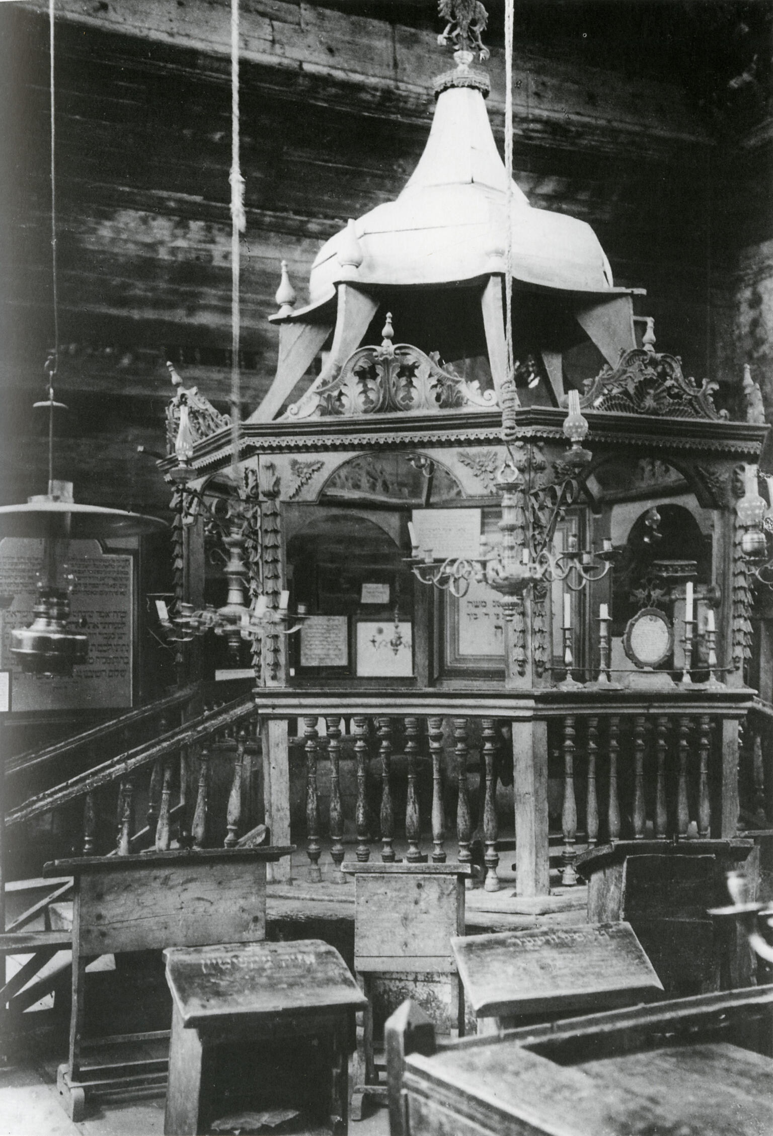 Photograph of platform with short staircase, conical roof, and elaborate pendant lamps.