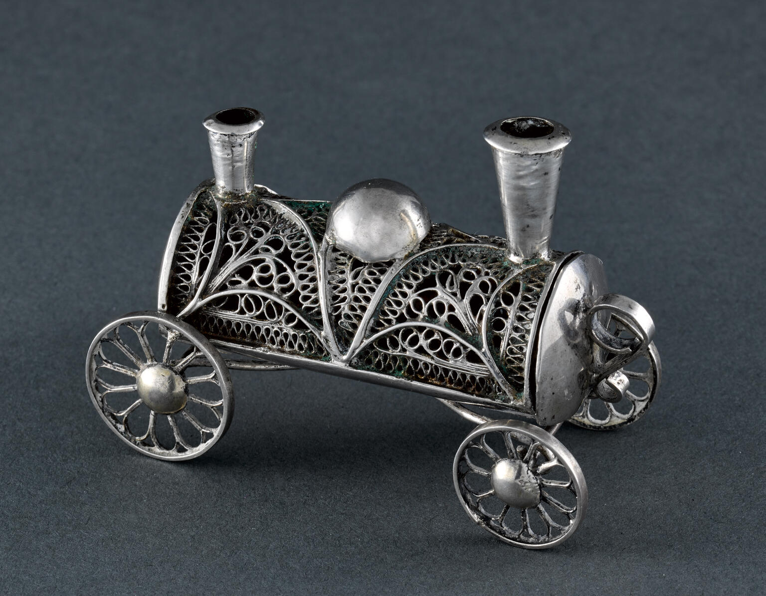 Filigree container in shape of a train car with four wheels and two smoke stacks.