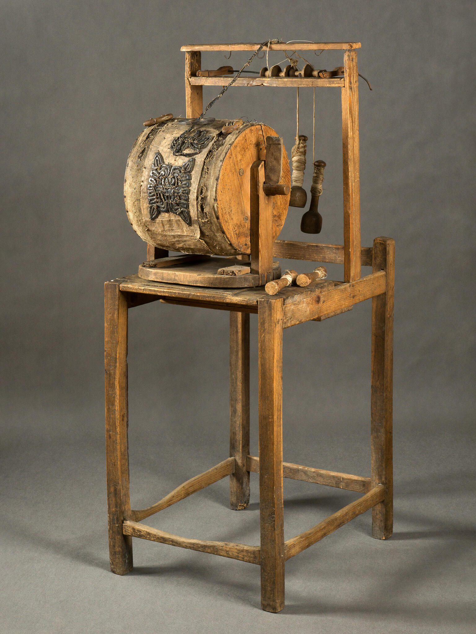 Wooden machine on four legs, with barrel and handle in center. Wooden machine on four legs, with barrel and handle in center.