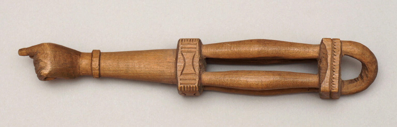Wooden pointer in shape of hand on one end, and bands etched with geometric patterns in center and other end.