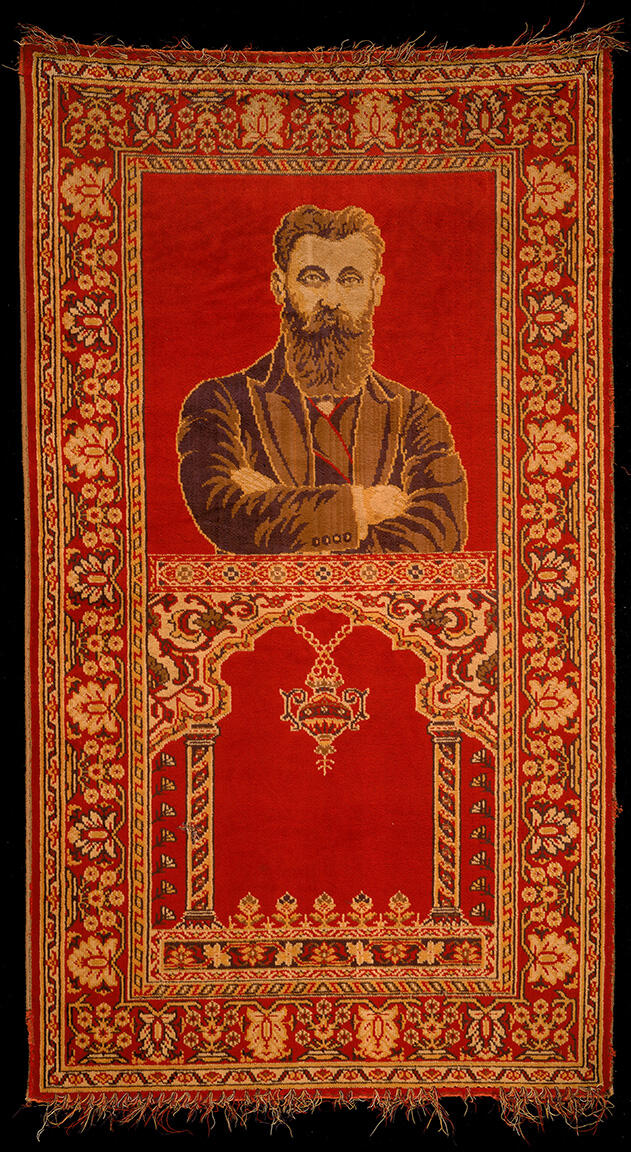 Rug depicting a bearded man with crossed arms on top half, and two columns and hanging lamp on bottom half, surrounded by decorative border. Rug depicting a bearded man with crossed arms on top half, and two columns and hanging lamp on bottom half, surrounded by decorative border.