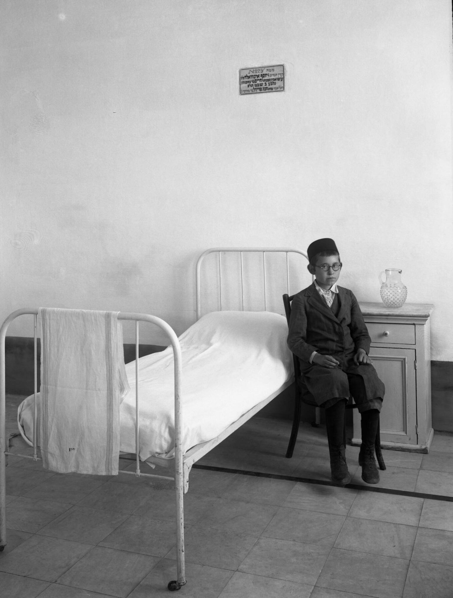 Photography of young boy sitting next to bed and nightstand. Photography of young boy sitting next to bed and nightstand.