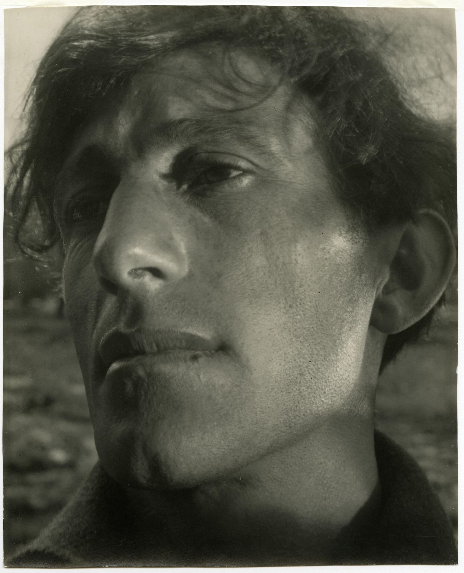 Close-up photograph of man's face. He has no expression and is looking to his right.