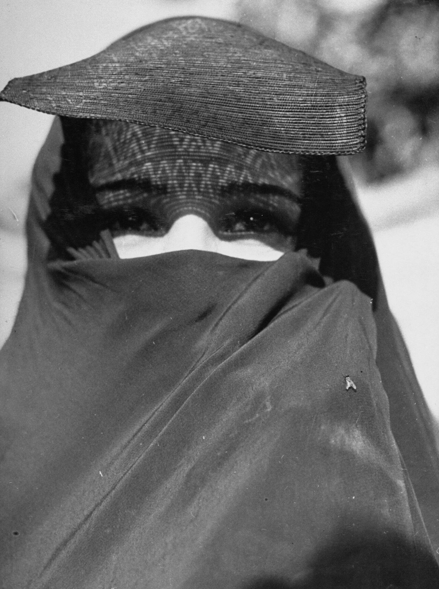 Photograph of veiled woman facing viewer with only her eyes exposed. Photograph of veiled woman facing viewer with only her eyes exposed.