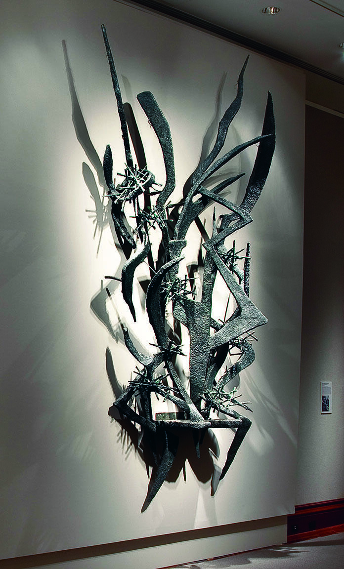 Large-scale abstract sculpture of sharp metal lines and edges installed on wall.