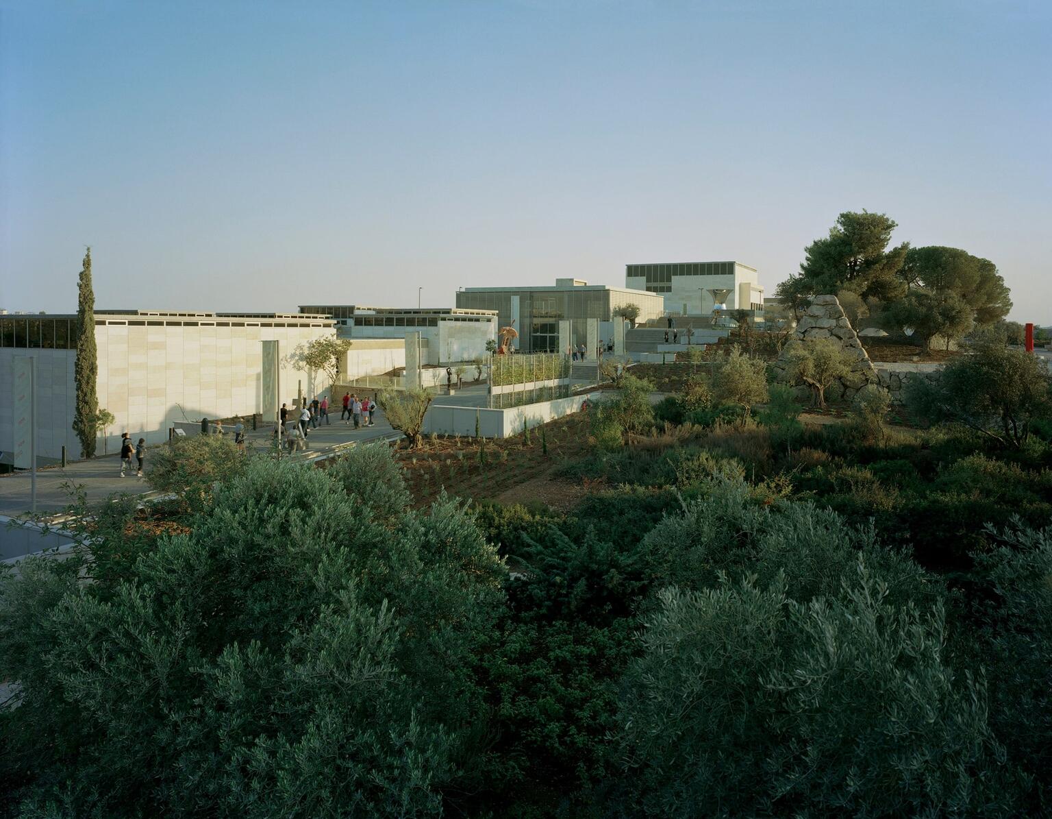 Photograph of several low buildings on a hill surrounded by trees. Photograph of several low buildings on a hill surrounded by trees.