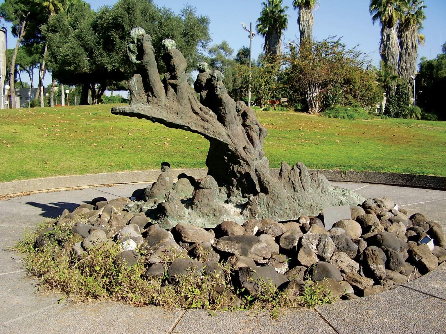 Bronze monument set in a circular courtyard surrounded by grass and trees.