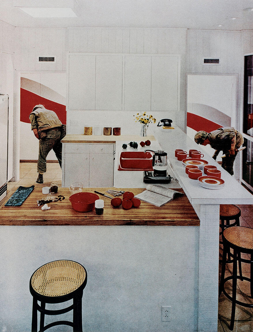 Photomontage depicting two soldiers surveying terrain outside the back of a modern kitchen, with cookware and mugs set out on the countertop and several stools along counter.