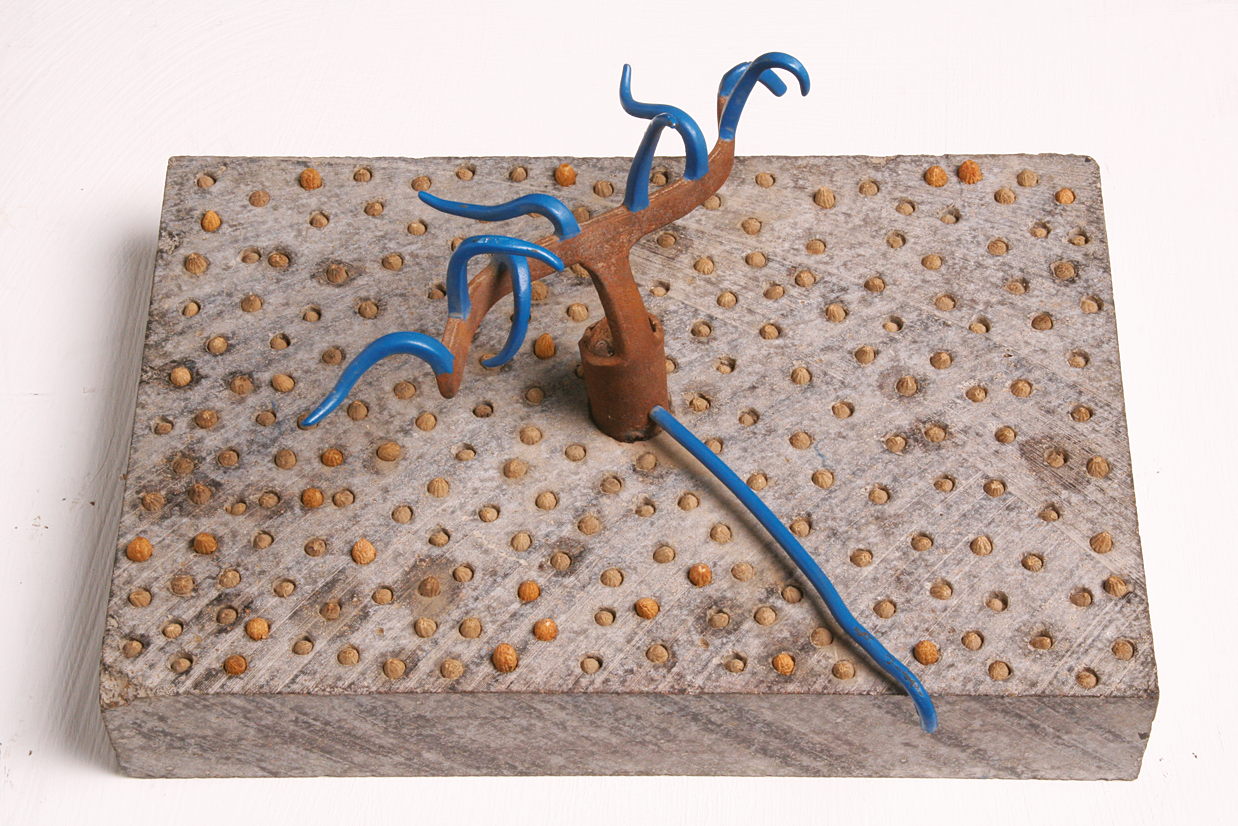 Abstract sculpture featuring iron lines protruding from cement base covered in small circles. Abstract sculpture featuring iron lines protruding from cement base covered in small circles.