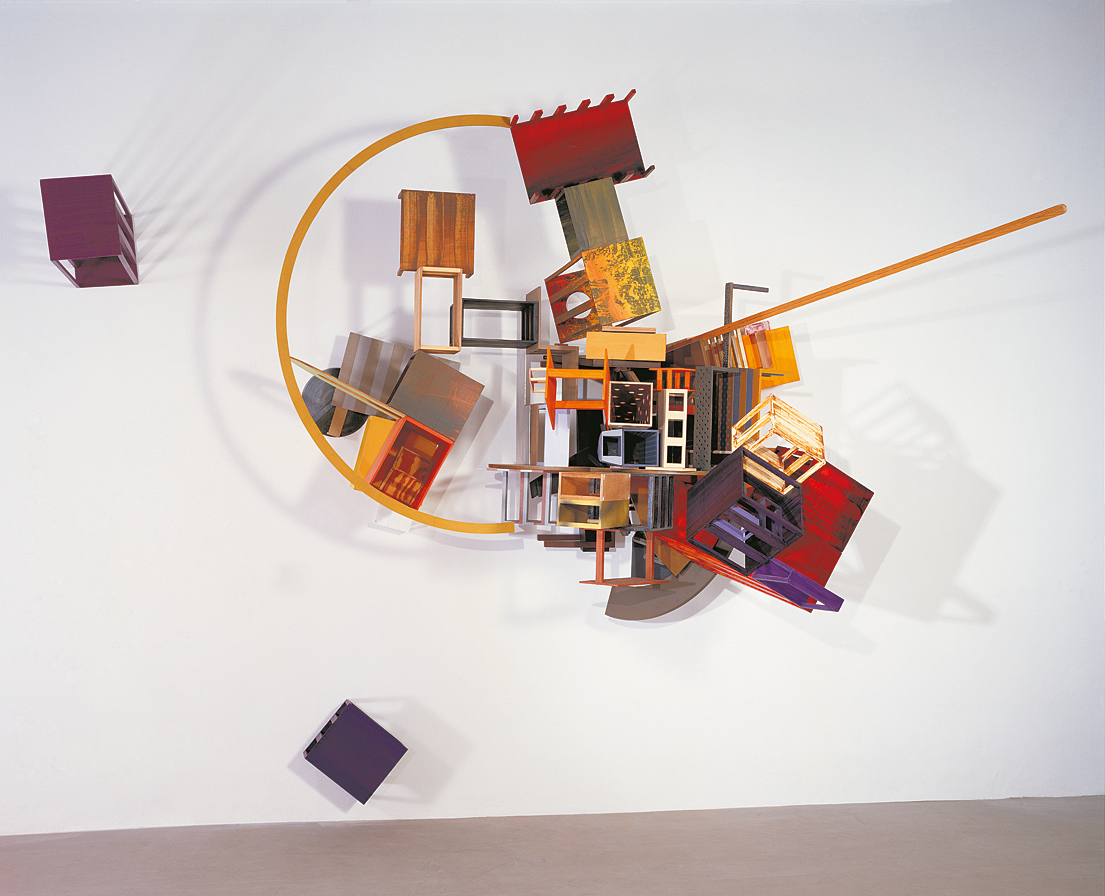 Industrial paint on wood sculpture mounted on wall featuring half moon shaped piece of wood and boxes.