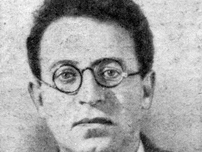 Black and white photo of a man with round spectacles and a necktie.