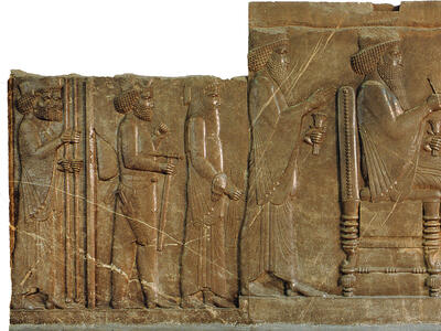 Relief of man sitting on throne with figures standing on either side.