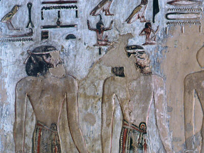 Mural of two figures looking at each other under hieroglyphs.