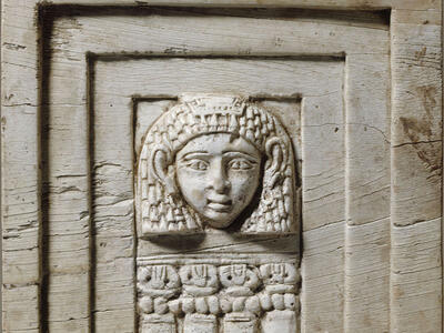 Rectangular relief of face framed in rectangular layers and four small columns below.