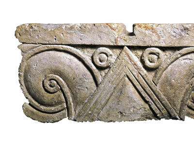 Limestone capital with triangles and carved palmette design.